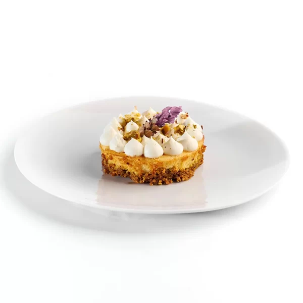 Cremoso pay de queso crema y de cabra, crust de galleta con pistache caramelizado.